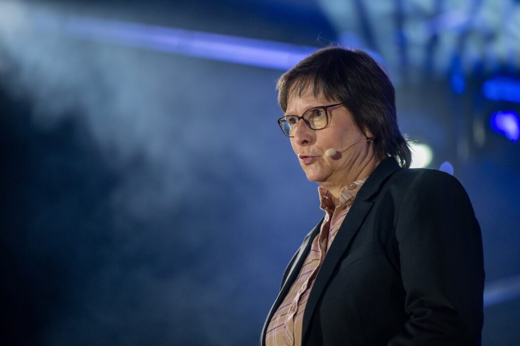 Petra Borchardt spricht auf einer Bühne mit Mikrofon.